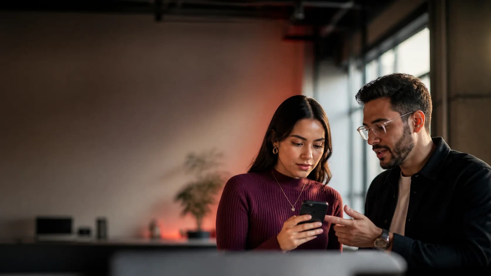 Dos profesionales revisan una aplicación móvil en un teléfono